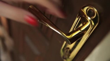 Kadının el kırmızı çivi ile altın doorhandle itmek ve yürümek.