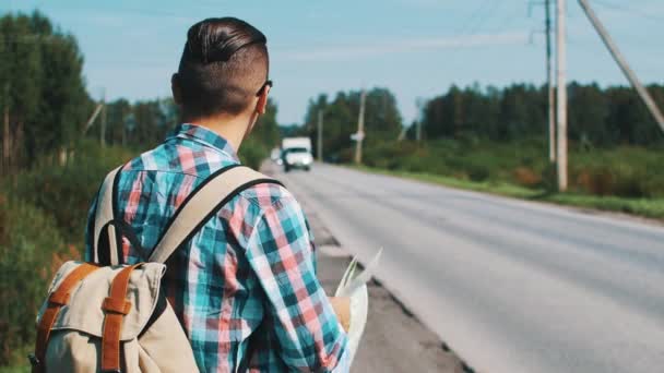 Parte posterior del joven con mapa autoestop en la carretera en verano día soleado . — Vídeo de stock