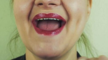 Kadın kırmızı pomad dokunmatik ağzına ön kamera ile. Maymun oynamak. Diş. Yüz