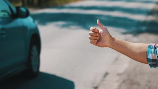 Junge trampt an einem sonnigen Sommertag auf der Straße. Reisende. Daumen hoch. Autos. — Stockvideo