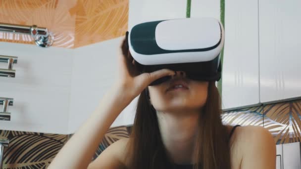 Chica sentada en el baño con máscara de realidad virtual en la cabeza. Mirando alrededor — Vídeos de Stock