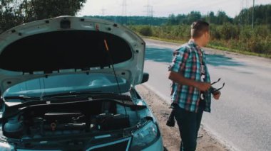 Çocuk yolda kırık arabada otur. Otostop. Yardım bekliyorum. Başparmak yukarı. Yaz