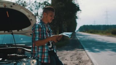 Çocuk yolda kırık arabada kal. Bekliyor. Açık kapüşonlu araba. Haritaya bak