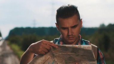 Yol kenarındaki haritaya bakan sırt çantası olan çocuk. Turist. Yaz güneşli gün