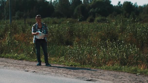 Un niño haciendo autostop en la carretera. Viajero. Pulgar hacia arriba. Mapa en manos. Viaje. — Vídeos de Stock