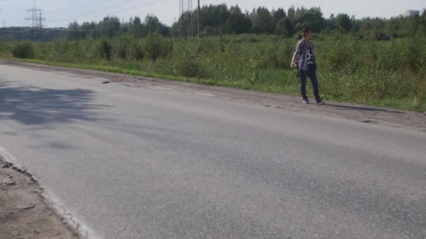 Young boy hitchhiking at road in sunny day. Tourist. Thumb up. Smoke cigarette. — Wideo stockowe