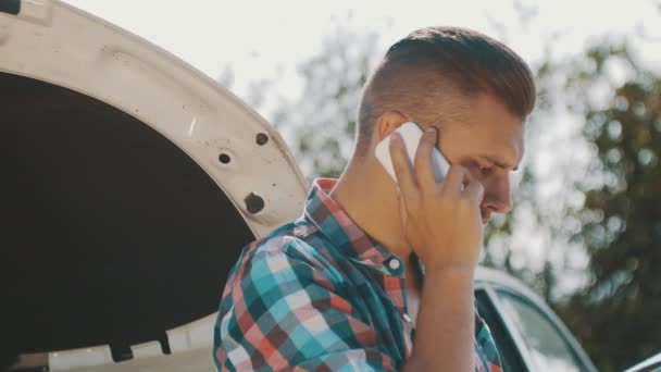 Το αγόρι μένει στο σπασμένο αμάξι στο δρόμο και μιλάει στο τηλέφωνο. Περιμένω βοήθεια. Κοιτάζοντας στο χάρτη — Αρχείο Βίντεο