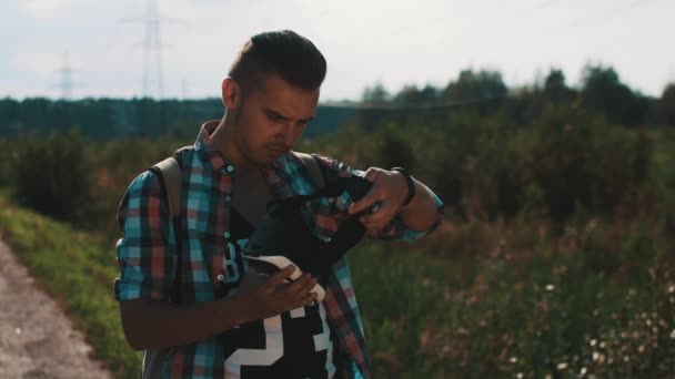 Garçon avec sac à dos regardant des lunettes de réalité virtuelle. Appareil. Jour d'été . — Video