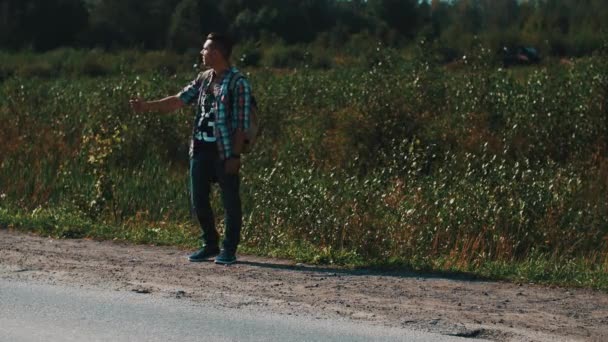 Young boy with backpack hitchhiking at road. Traveler. Thumb up. Summer day — Stockvideo