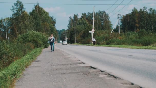 Junge mit Sonnenbrille, der mit Karte die Straße entlangläuft. Reisen. Per Anhalter. Daumen hoch — Stockvideo