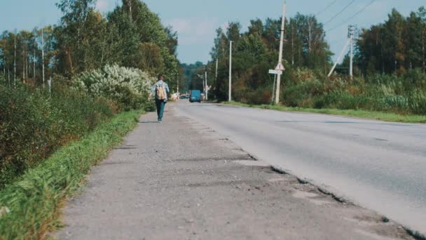 Niño caminando a lo largo de la carretera mantenga placa de cartón con la ciudad signo. Hacer autostop. Viajes — Vídeos de Stock