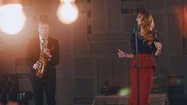 Jazz duet uitvoeren op het podium. Saxofonist in pak. Zanger in retro stijl. Verlichting — Stockvideo