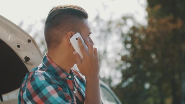 Rapaz, fica no carro avariado na estrada e fala ao telefone. À espera de ajuda. Mapa em mãos — Vídeo de Stock