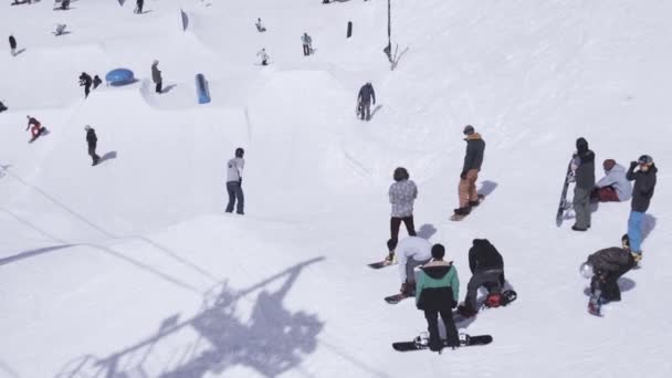 Skigebied. Snowboarder rit op helling, springen om springplanken. Berg. Zonnige dag — Stockvideo