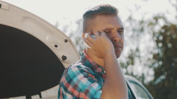 El chico se queda en el coche roto en la carretera y habla por teléfono. Esperando ayuda. Mapa en manos — Vídeos de Stock