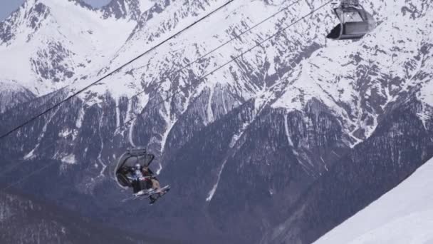 Paysage de montagnes enneigées par temps ensoleillé. Station de ski. Les gens roulent sur des remontées mécaniques . — Video