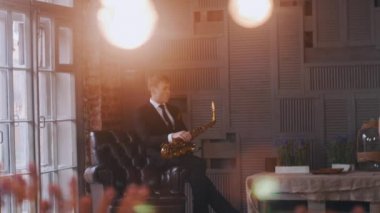 Sahnede sandalyede saksafoncu. Caz vokalisti mikrofonda performans sergiliyor. ışık