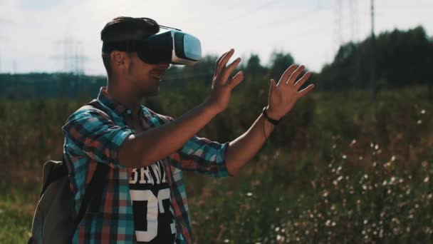 Garçon avec sac à dos regardant des lunettes de réalité virtuelle dans la rue. Appareil. Été . — Video