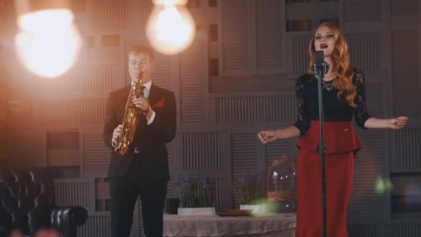 Le duo de jazz se produit sur scène. Saxophoniste en costume. Chanteuse dans un style rétro. Artiste — Video