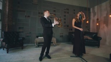 Saksafonuzla sahnede performans sergileyen parlayan elbiseli caz vokalisti. El kaldırın