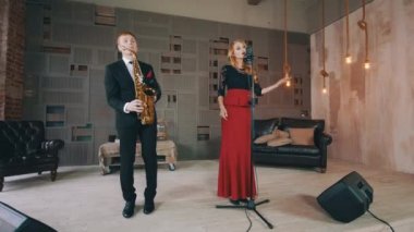 Sahnede caz düet. Saksafoncu ve vokalist. Retro tarzı elbise. Performans
