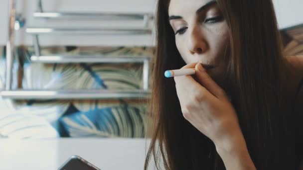 Dívka sedí v koupelně kohoutek smartphone. Kouření elektronické cigarety. Inhalovat páry — Stock video