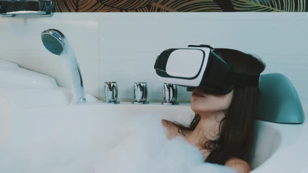 Девушка принять ванну, полную пены глядя эротическое видео в очки виртуальной реальности . — стоковое видео