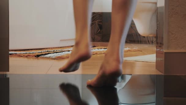 Mujer con las piernas desnudas caminar en el baño y sentarse en el inodoro. Deja la ropa interior. — Vídeo de stock