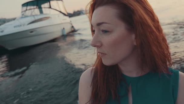 Attractive red hair girl in turquoise dress on motor boat. Summer evening. Water — Stock Video