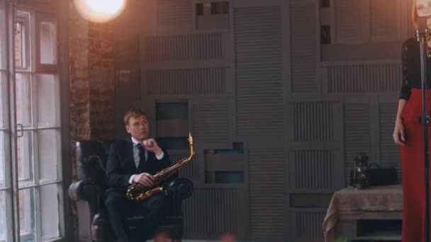 Jazz énekes végre a mikrofont. Saxophonist ül szék. Retro stílusú — Stock videók