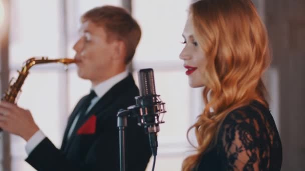 Aantrekkelijke vrouwelijke zanger zingen op het podium, dansen. Saxofonist. Jazz duet. — Stockvideo