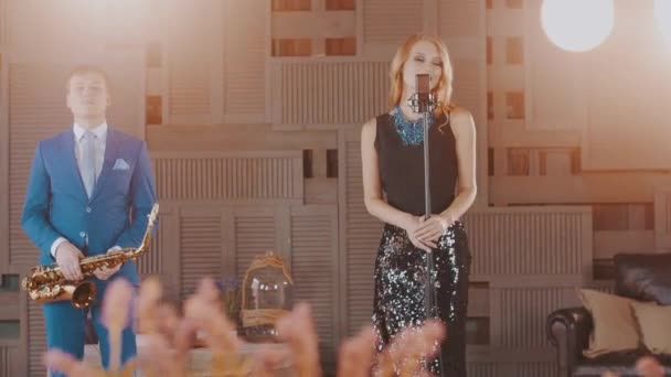 Джазовый вокалист в светящемся платье и саксофонист в синем костюме выступают на сцене . — стоковое видео