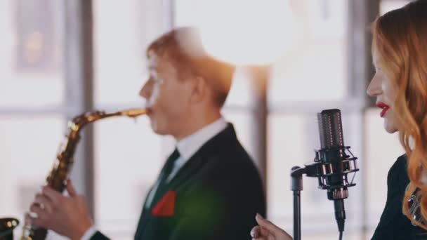 Atraktivní zpěvačka na jevišti, tančit. Saxofonista hraní. Jazzových duet. — Stock video