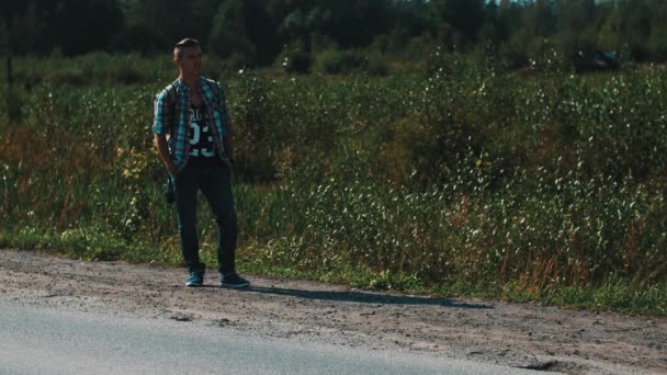 Jeune garçon avec sac à dos auto-stop sur la route. Voyageur. Levez le pouce. En bordure de route . — Video