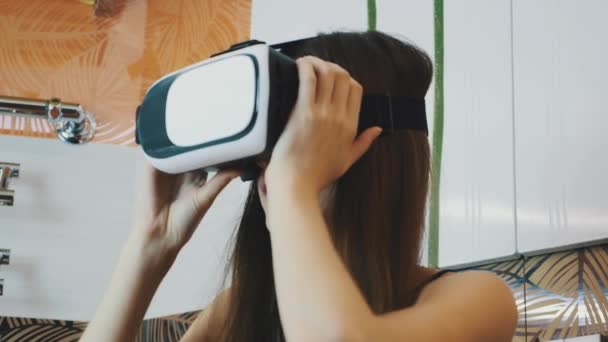 Chica sentada en el baño en gafas de realidad virtual en la cabeza. Mirando alrededor — Vídeos de Stock