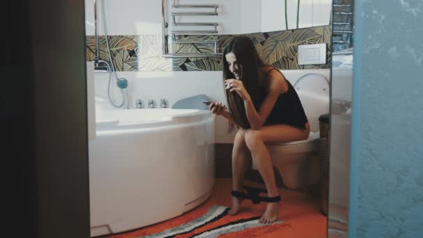 Young girl sit on toilet. Tap on smartphone. Smoke electronic cigarette. Steam — Αρχείο Βίντεο