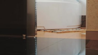 Mavi bornoz kız görünümünü banyoya yürümek ve üzerinde beyaz banyo otur.