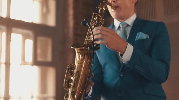 Saxofonista en traje azul toca jazz en saxofón dorado con micrófono. Elegancia — Vídeos de Stock