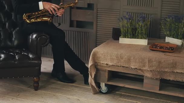 Saxofonist in Abendjacke sitzt auf Stuhl mit goldenem Saxophon. Jazzkünstler. — Stockvideo
