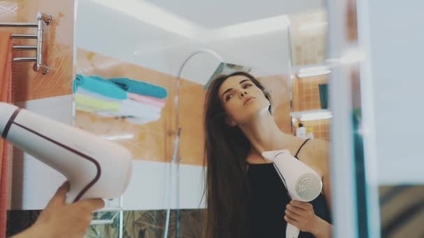 Çekici genç kız banyoda saç kurutma makinesi tarafından kuru saçlar. Aynaya poz. — Stok video