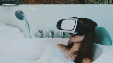 Kız almak banyo köpük banyoda sanal gerçeklik gözlük ile dolu. Gülümseme