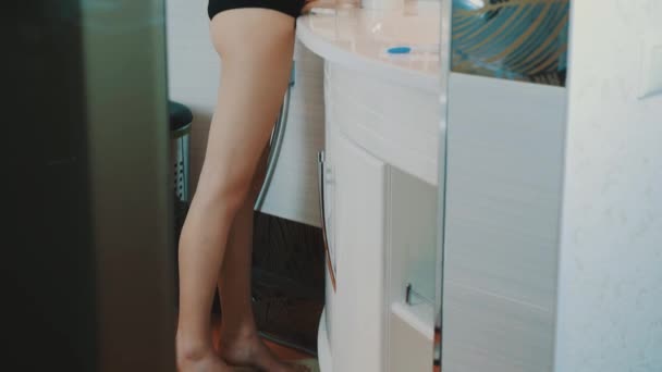 Giovane ragazza bruna in top look nero nello specchio in bagno. Faccia di tocco. Sorridi — Video Stock