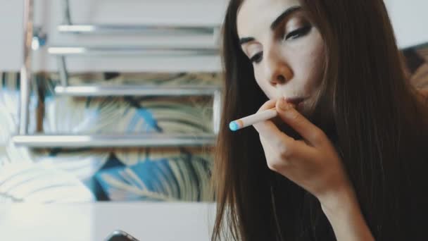 Dívka sedící v koupelně pomocí smartphonu. Kouření elektronické cigarety. — Stock video