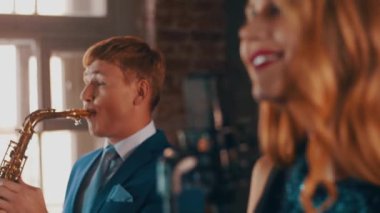 Mavi elbiseli saksofoncu ile sahnede performans çekici caz vokalisti. Canlı