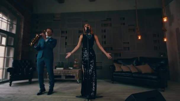 Jazz vocalist in glowing dress performing on stage with saxophonist. Raise hands — Stock Video