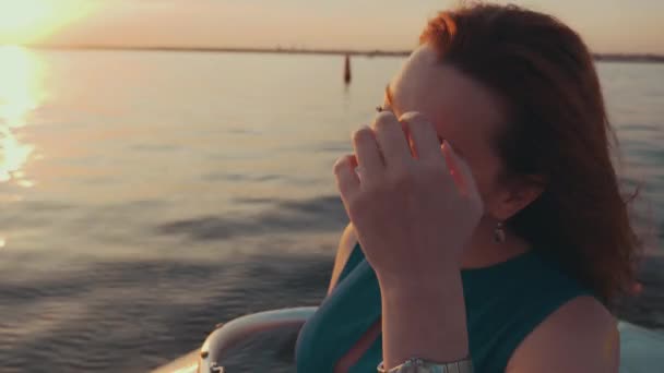 Rood haar meisje in turquoise jurk varen op een motorboot. Geniet van de prachtige zonsondergang. — Stockvideo