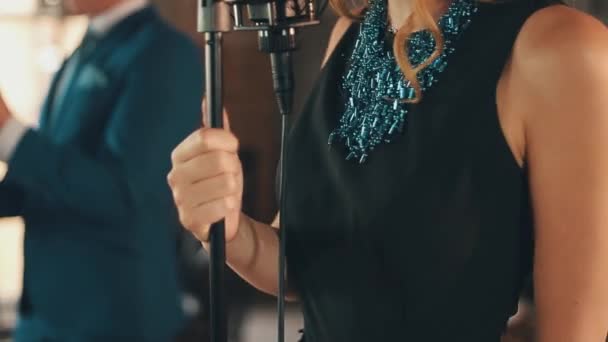 Джазовий вокаліст у чорній сукні, блакитне намисто виступає на сцені з музикантом — стокове відео