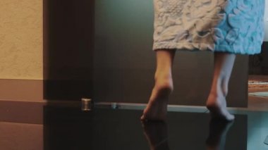 Kız banyoda bornoz yürüyüşte sessizce, banyo üzerinde otur. Işığı.