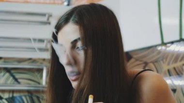 Banyo musluk smartphone içinde oturan genç kız. Elektronik sigara.