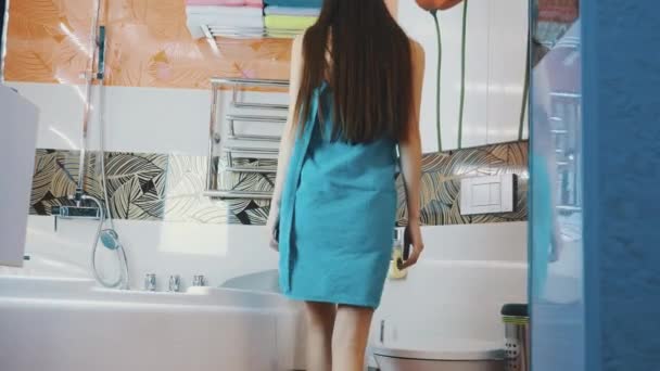 Young girl in blue towel walk in bathroom opening water faucet. Touch the water — Stock Video